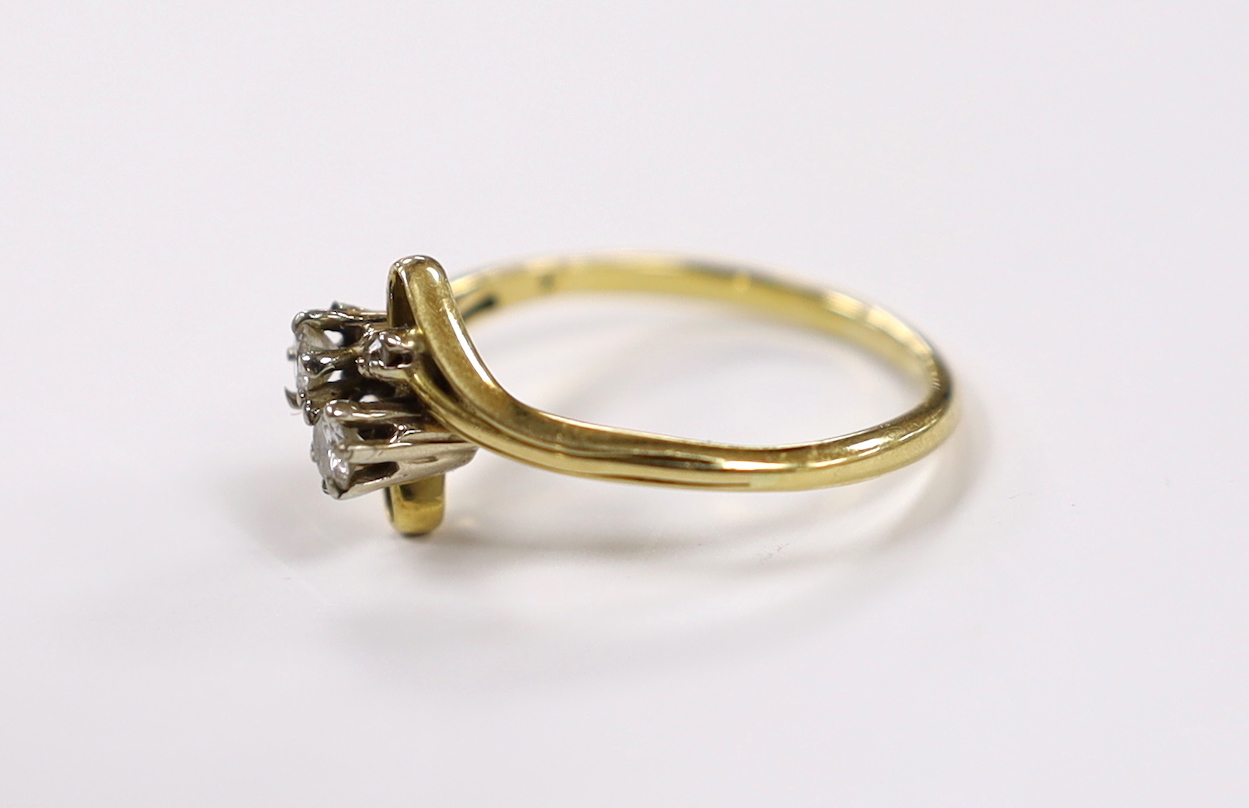 A yellow metal and graduated four stone diamond set crossover ring, size R, gross weight 3.4 grams.